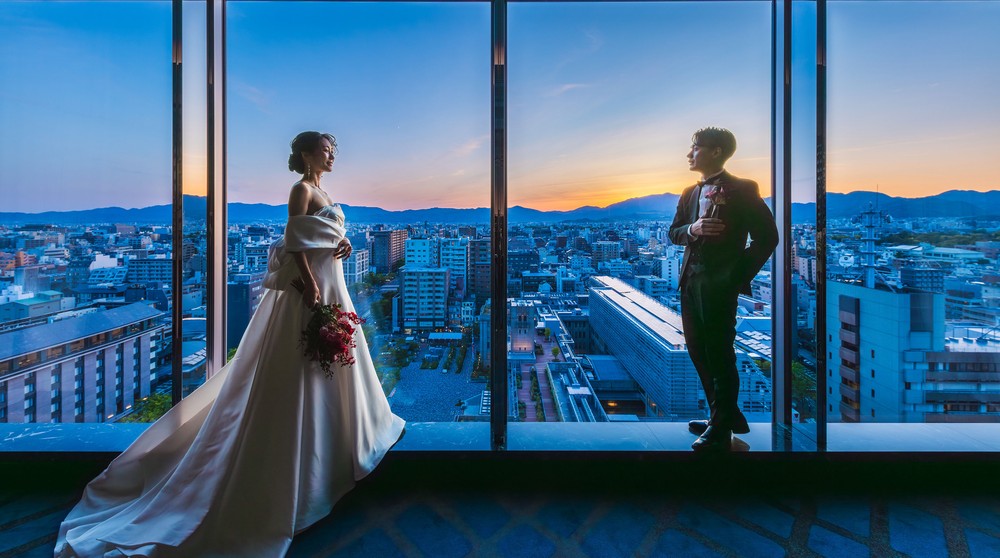 ホテルオークラ京都の最上階にあるスカイバンケット「アポロン」で美しい夕景とともに見つめあう新郎新婦